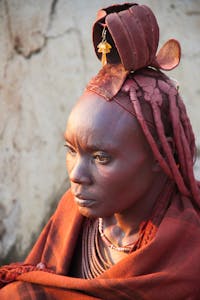 Portrait of Himba woman wearing traditional clothing and headdress, captured in Namibia.