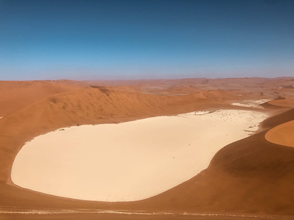 Stunning aerial view of Sossusvlei in Namibia's Namib Desert, featuring vast sand dunes and a white clay pan.