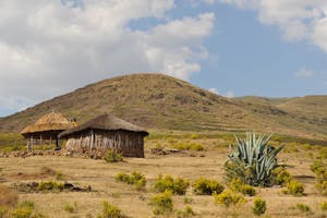 Scenic view of traditional huts in a dry, mountainous African landscape under a blue sky.